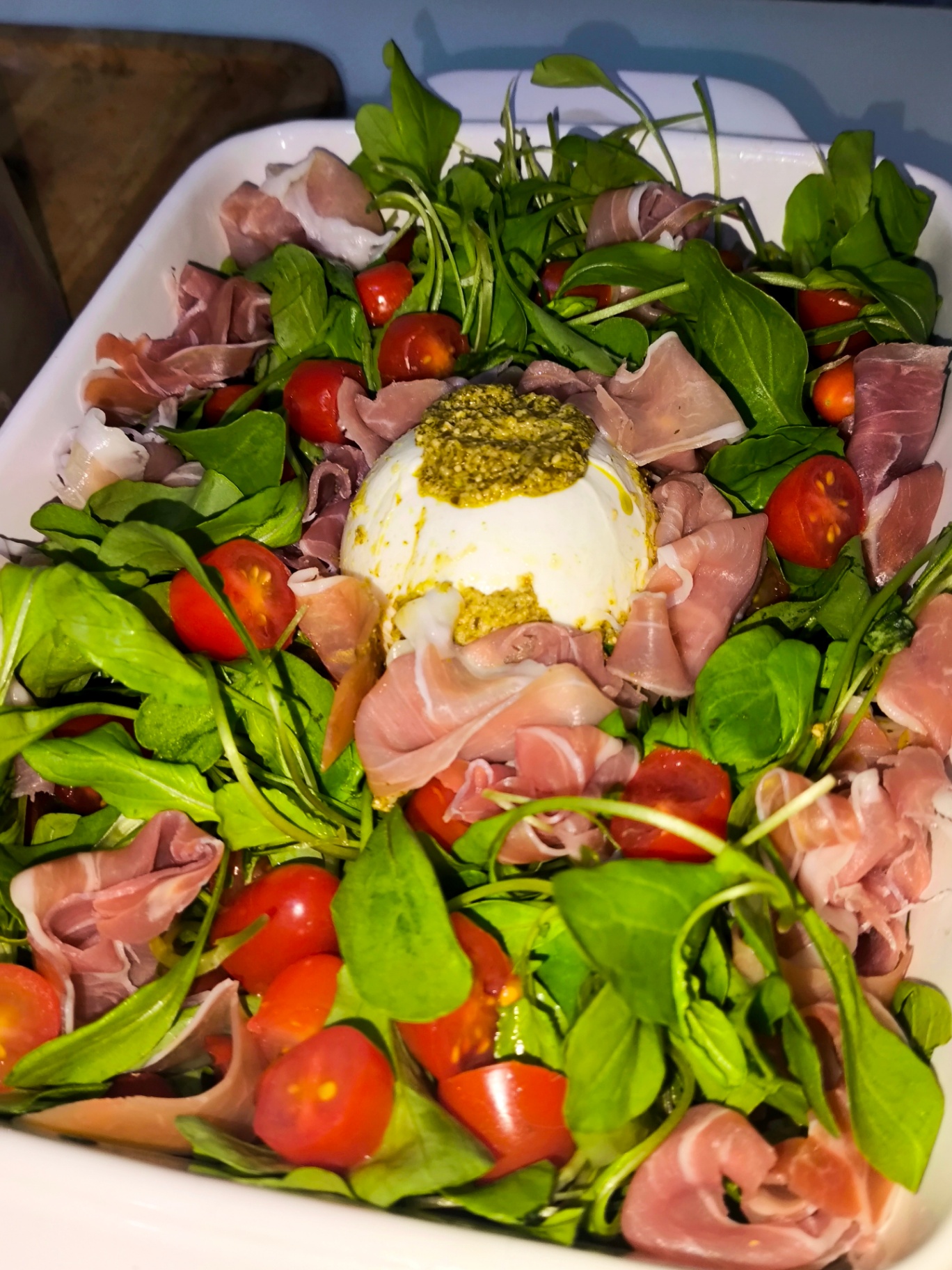 Burrata ao pesto sobre cama de rúcula, presunto cru e tomatinhos cereja